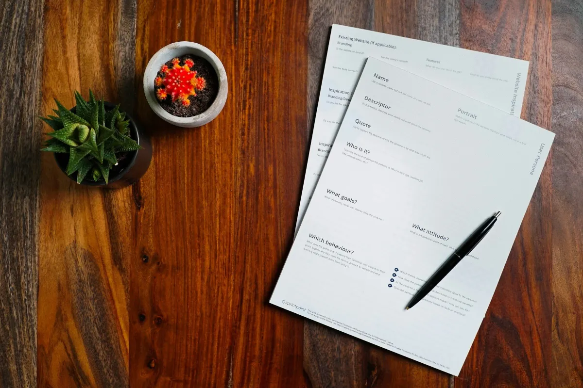 Printed documents and a pen on a wooden desk