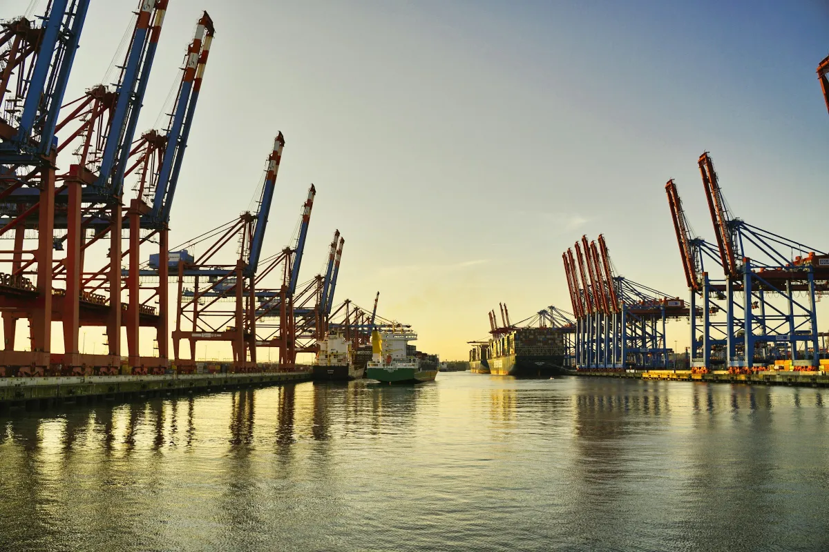 Barisan kren terminal kontena di sepanjang pelabuhan dalam cahaya keemasan