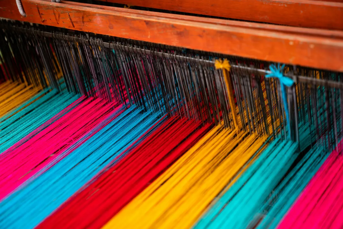 Colourful warp threads stretched across a wooden weaving loom